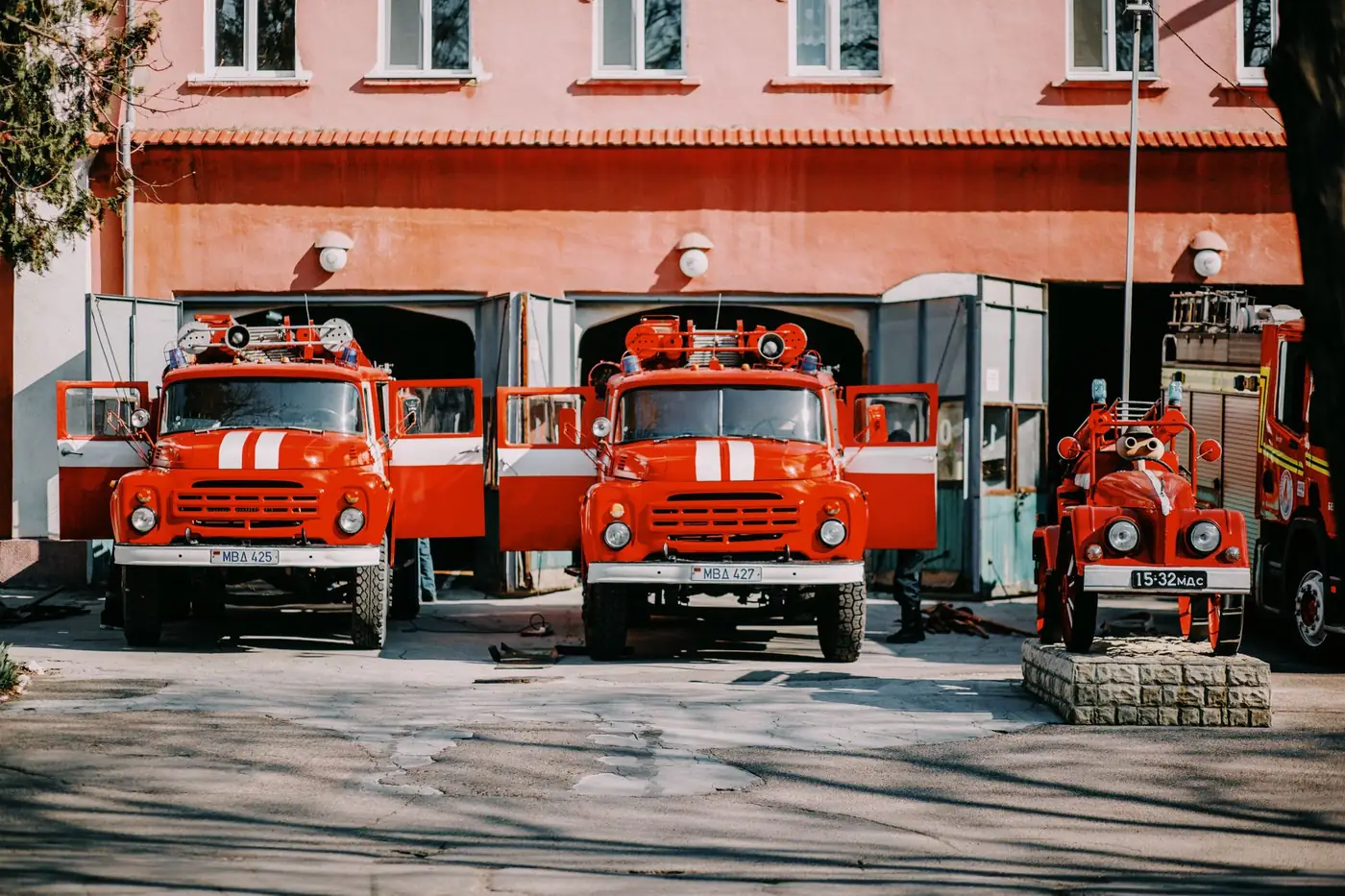 Red fire trucks parked side by side outside a fire station