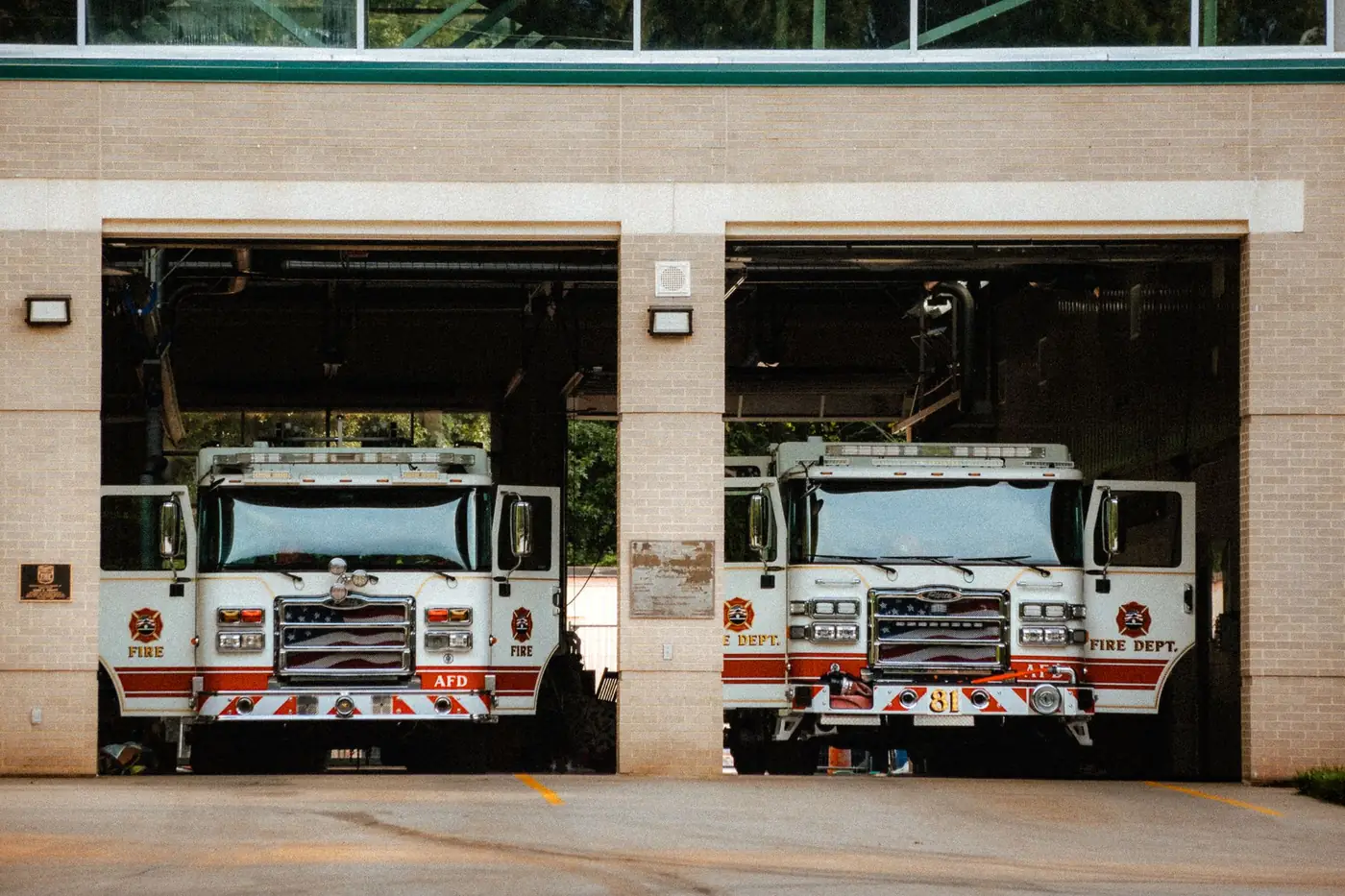 Two fire engines parked in the open bays of a fire station