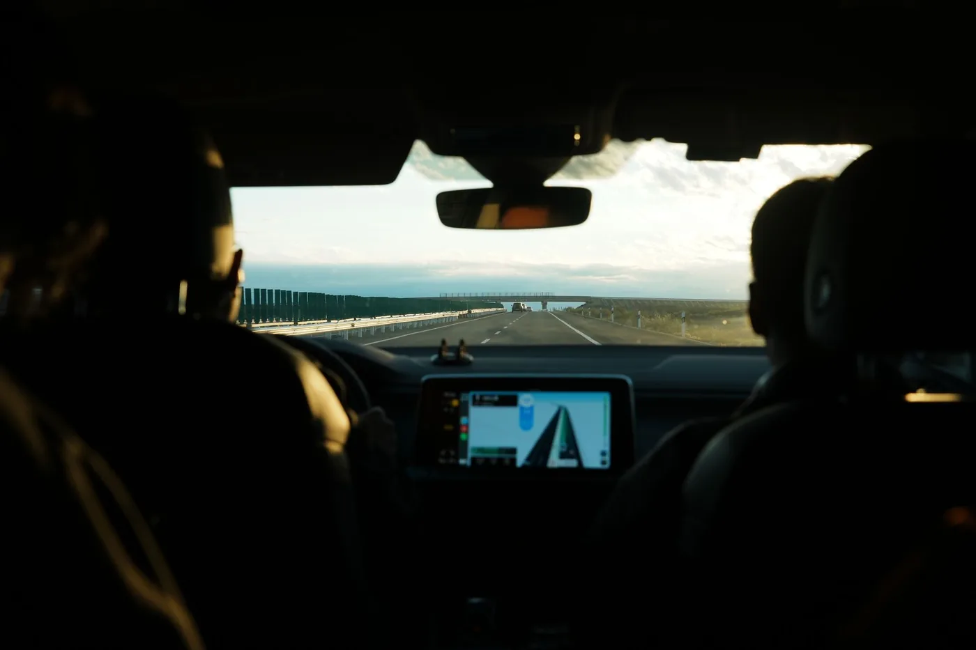 View from inside a car during a road trip showcasing an open highway and digital navigation screen.