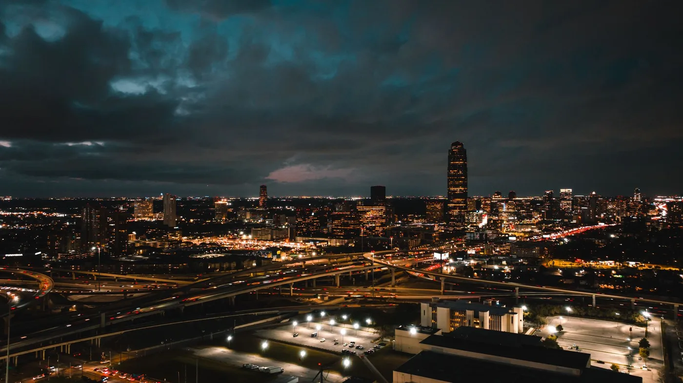 A breathtaking aerial shot of Houston's vibrant cityscape at night, featuring busy freeways and illuminated buildings.