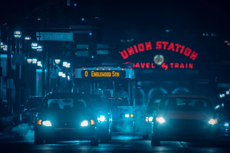 Nighttime traffic in front of Denver's iconic Union Station with illuminated signs and vehicles.