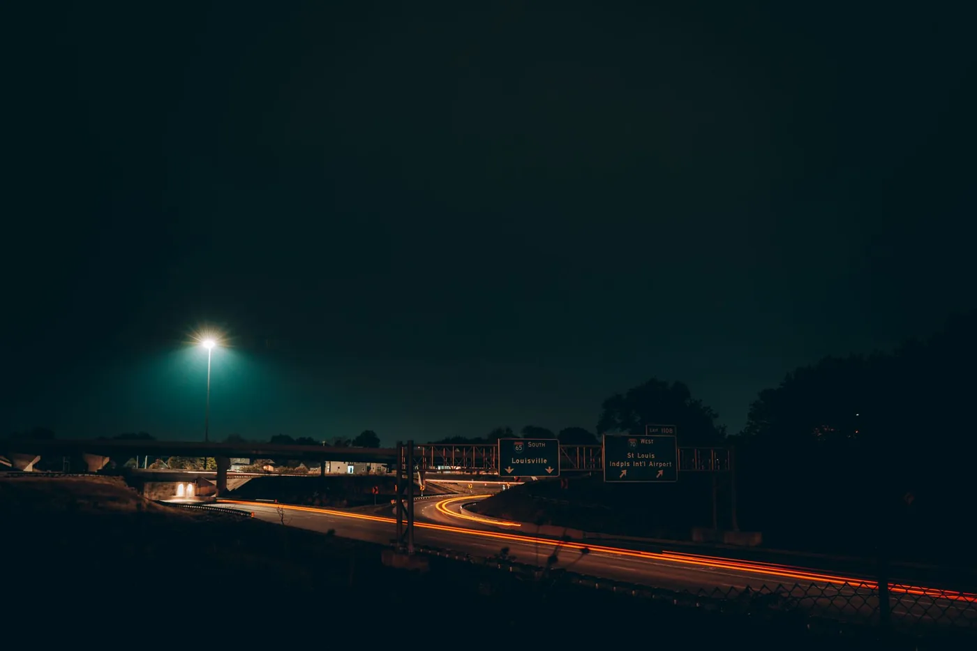 Captivating long exposure shot of Indianapolis highway at night with light trails and road signs.