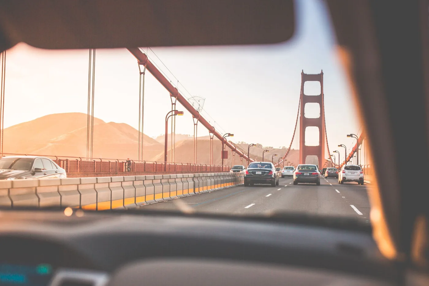 A scenic drive across San Francisco's iconic Golden Gate Bridge during sunset, capturing vehicles on the road.