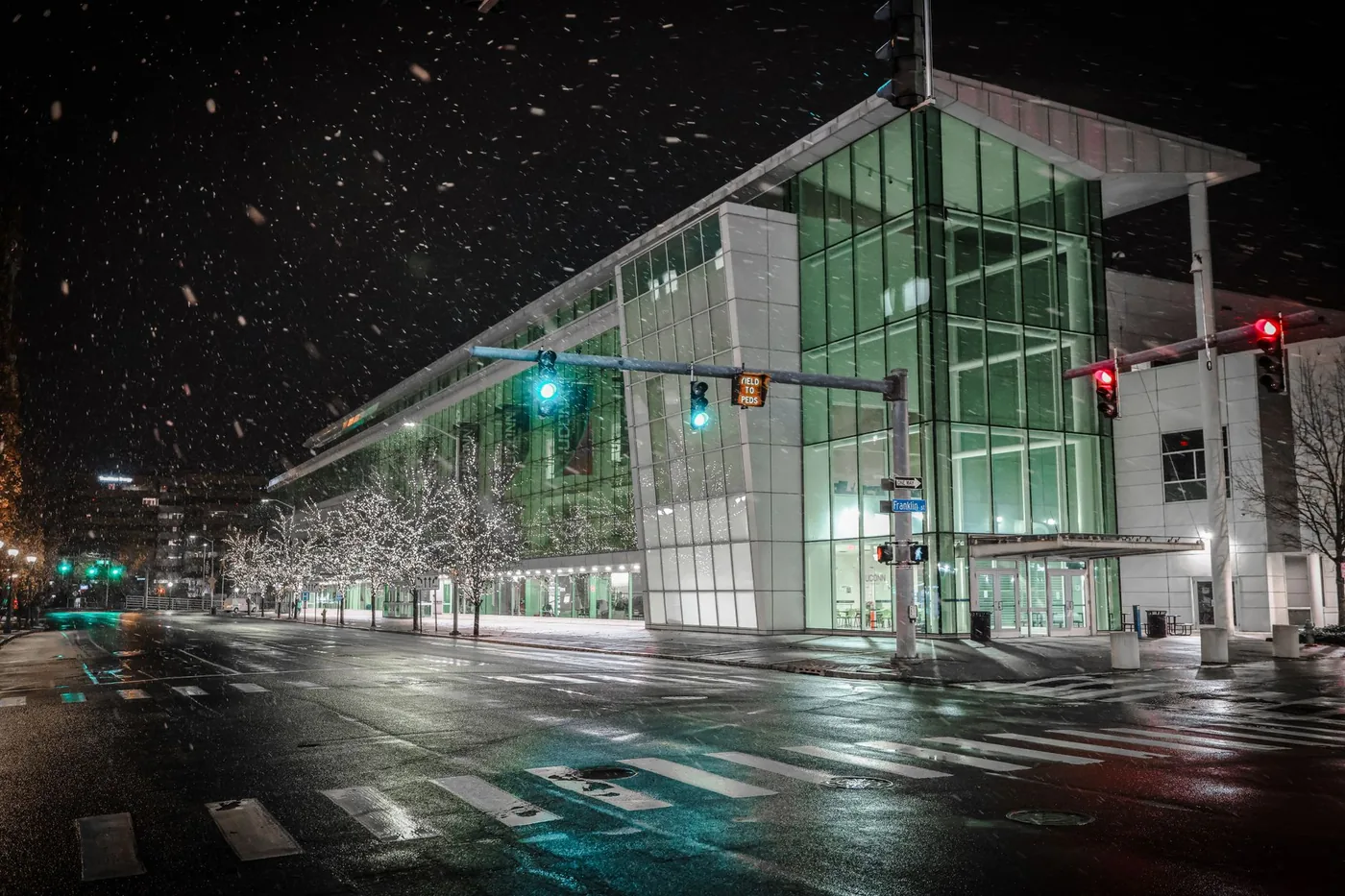 Modern glass building in downtown Stamford during a snowy winter night.