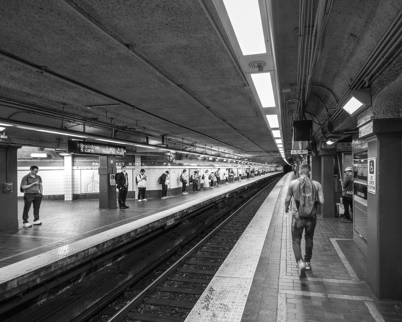 Black and white photo of a Boston subway station with people waiting on the platform.