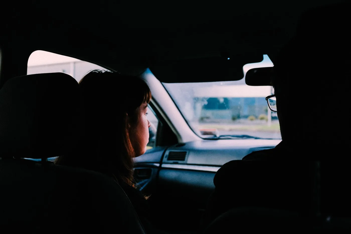 Two individuals captured inside a car, traveling during dusk, showcasing a serene driving experience.