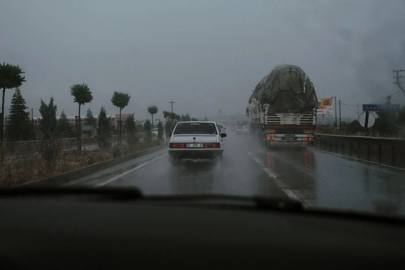 Vehicles driving on a wet highway during rainfall, showcasing road transportation challenges.