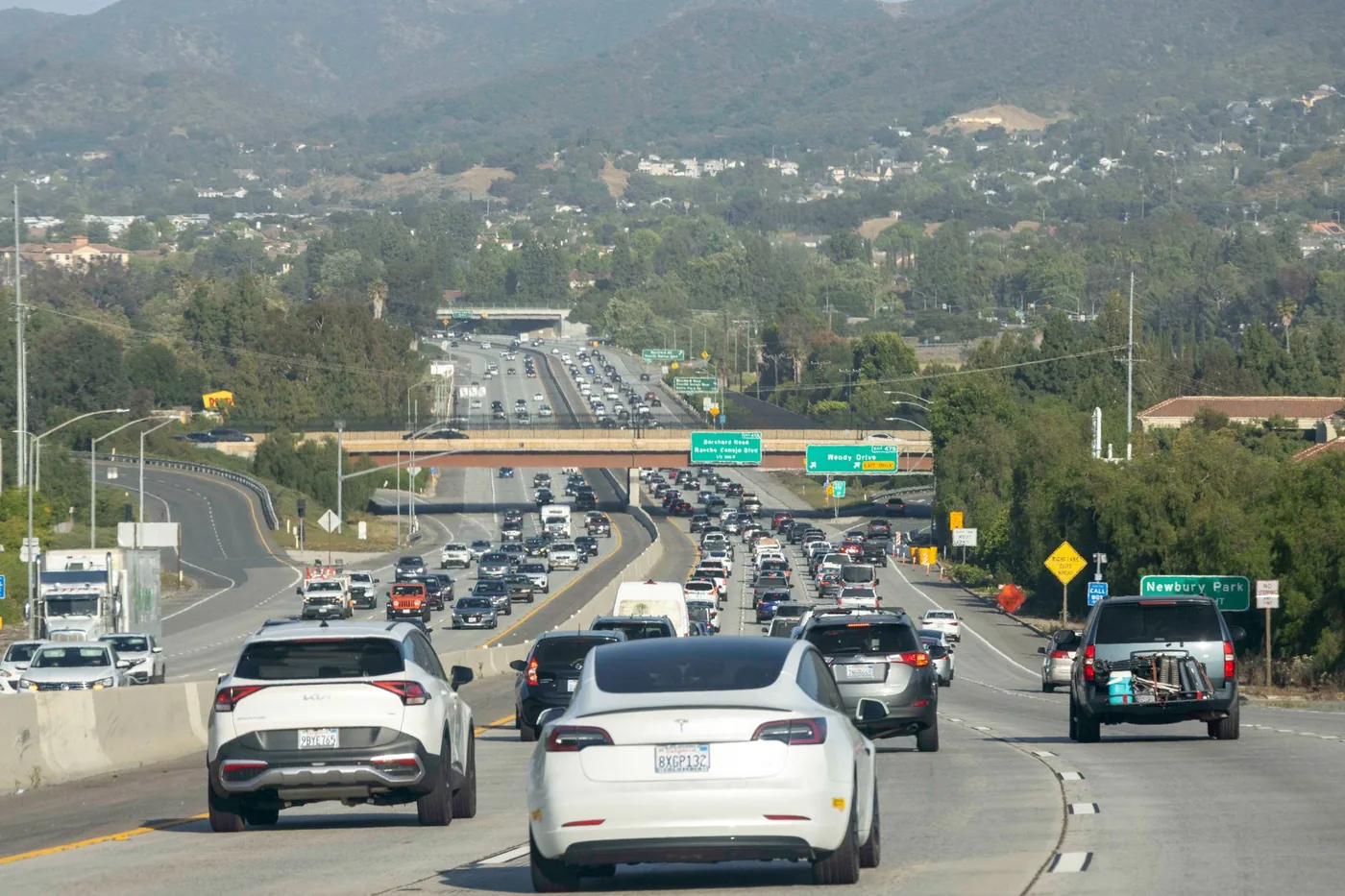 Heavy traffic on a Los Angeles highway with visible road signs and cars under a clear sky.