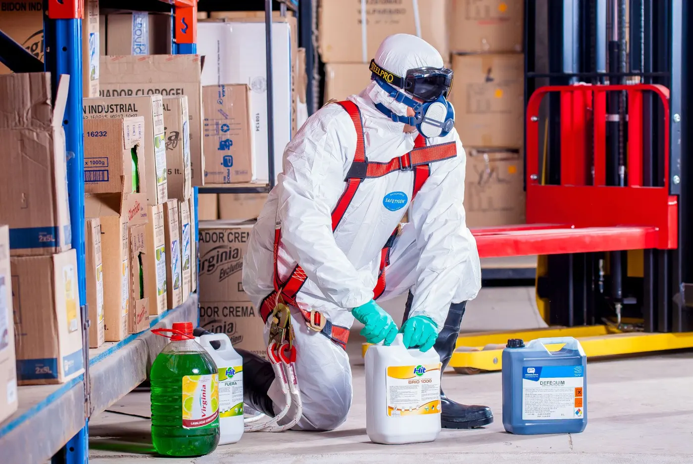 Industrial worker in protective gear handling chemical containers