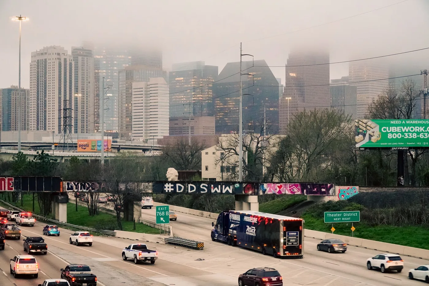 Commuters on a foggy morning with Houston skyline partially obscured by dense fog.