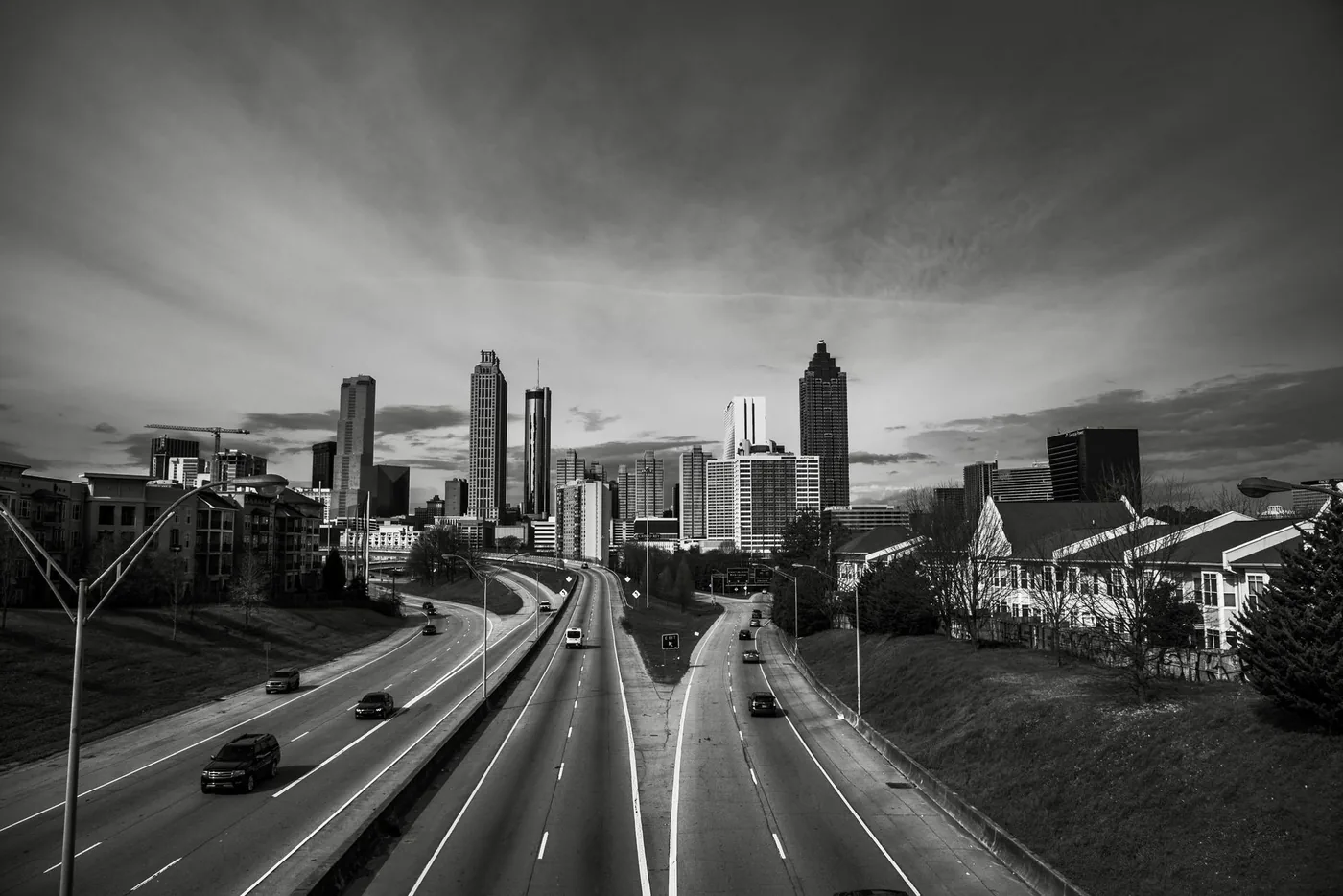 Black and white aerial view of Atlanta skyline with busy highway foreground.