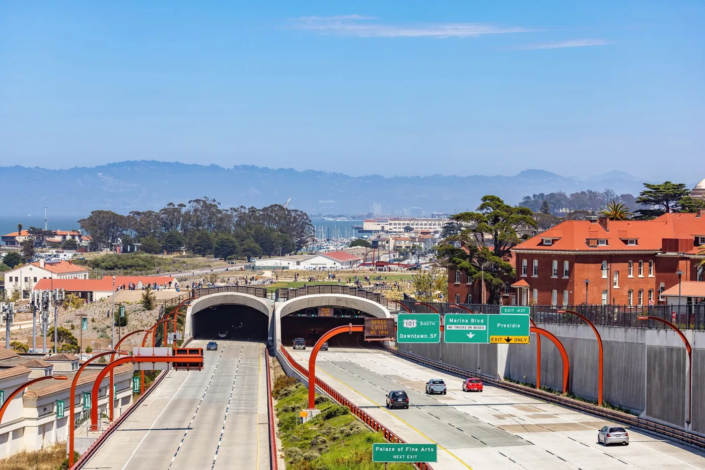 Aerial view of Highway 101 entering a tunnel with clear sky and buildings in San Francisco.