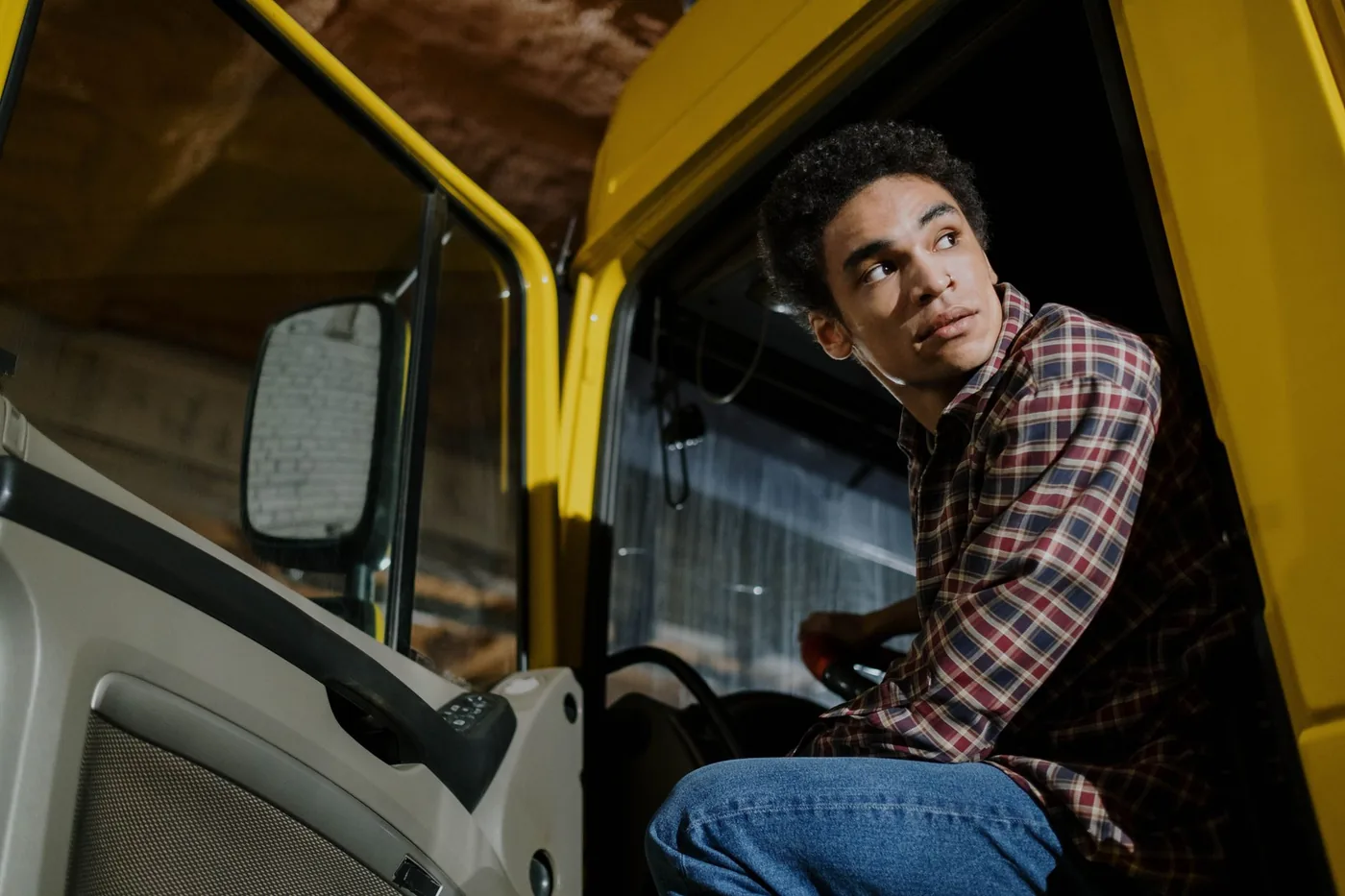 Truck driver in a plaid shirt looking out from his cab at night during a night-shift stretch