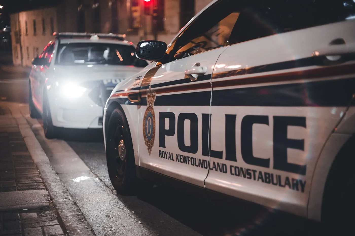 Police cars parked on a street at night