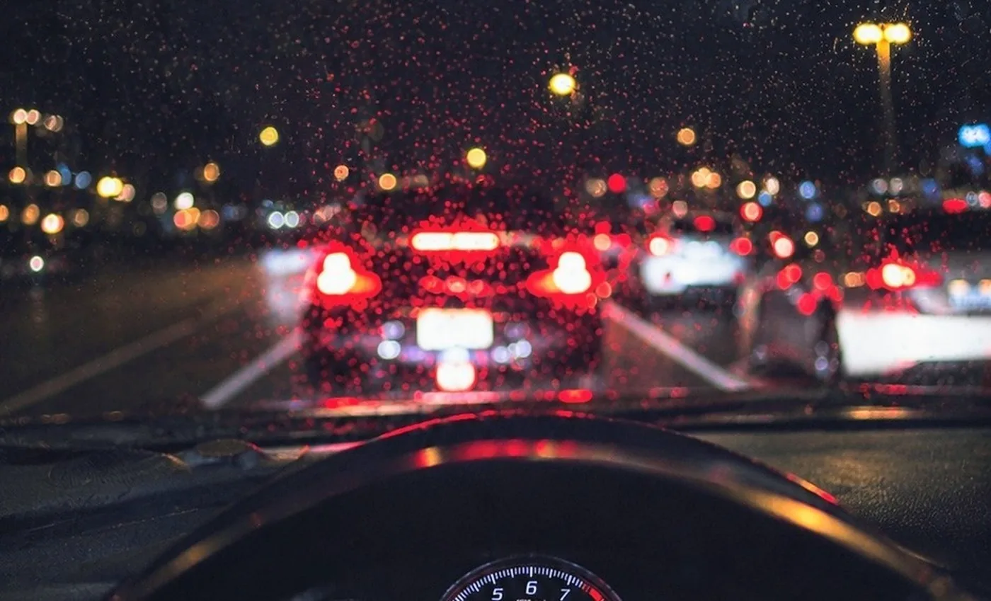 Rainy night traffic through a wet windshield, capturing vibrant bokeh lights.