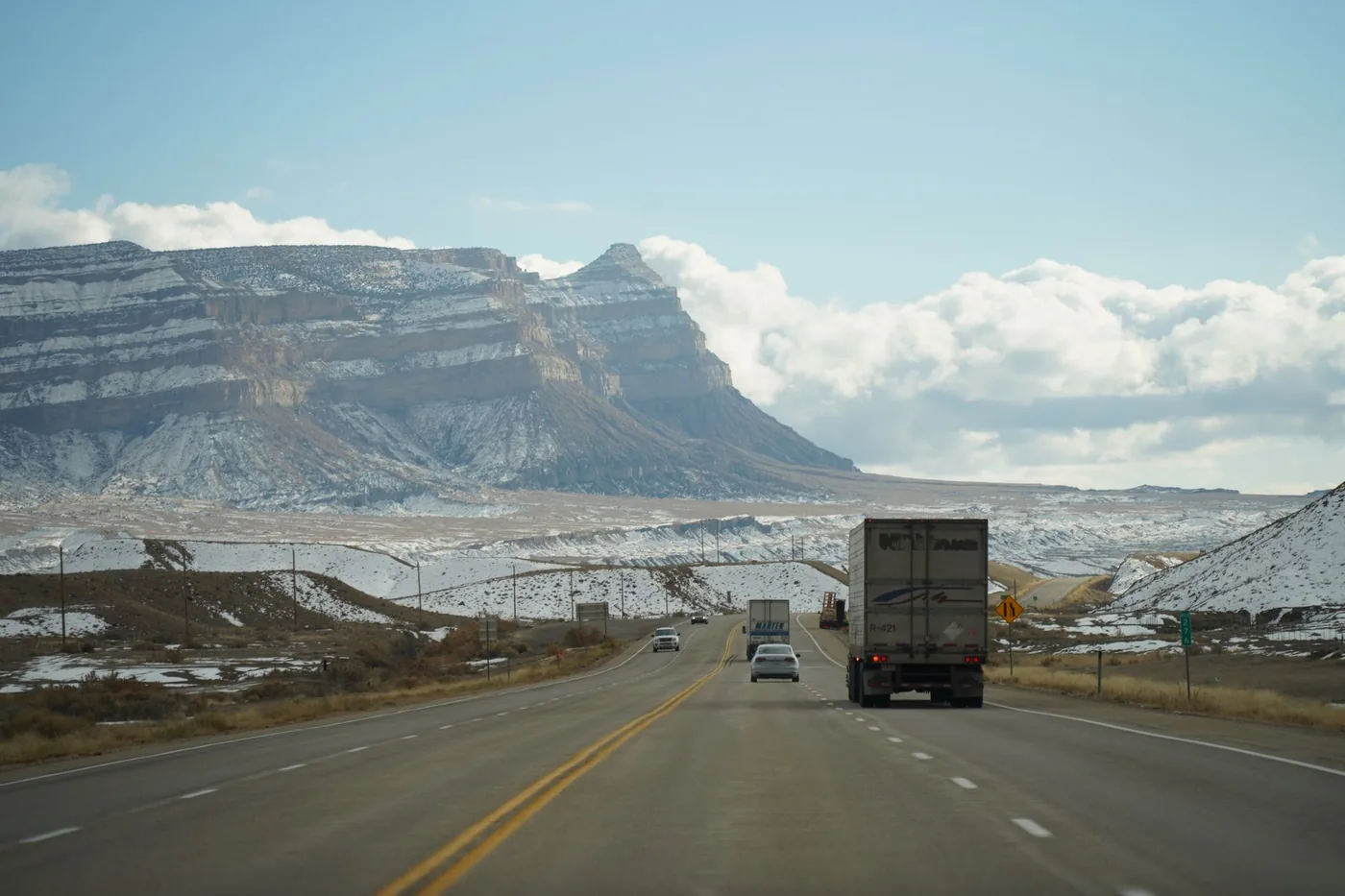 A winter road trip through mountainous terrain with vehicles on a scenic highway.