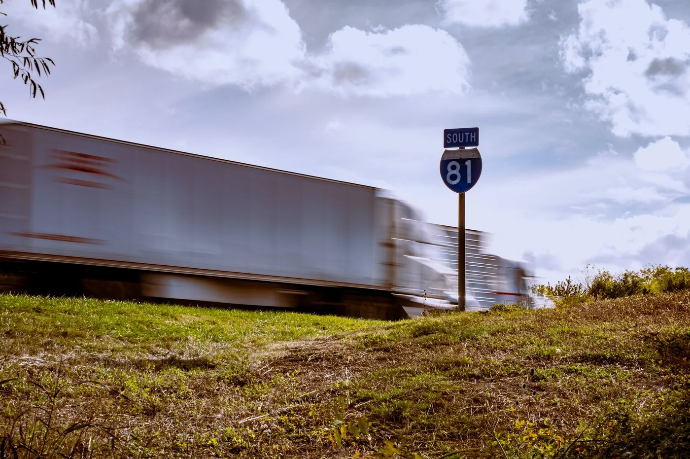 Blurred truck on Interstate 81 South with clear blue sky and grassy foreground.