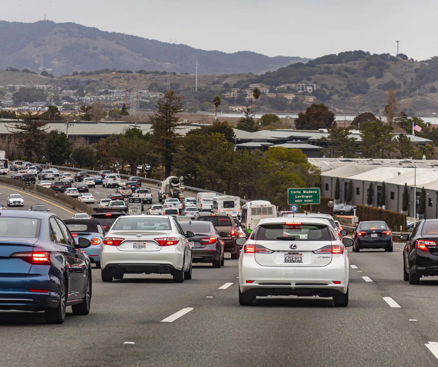 A busy highway scene in California with numerous vehicles and mountainous backdrop under overcast skies.