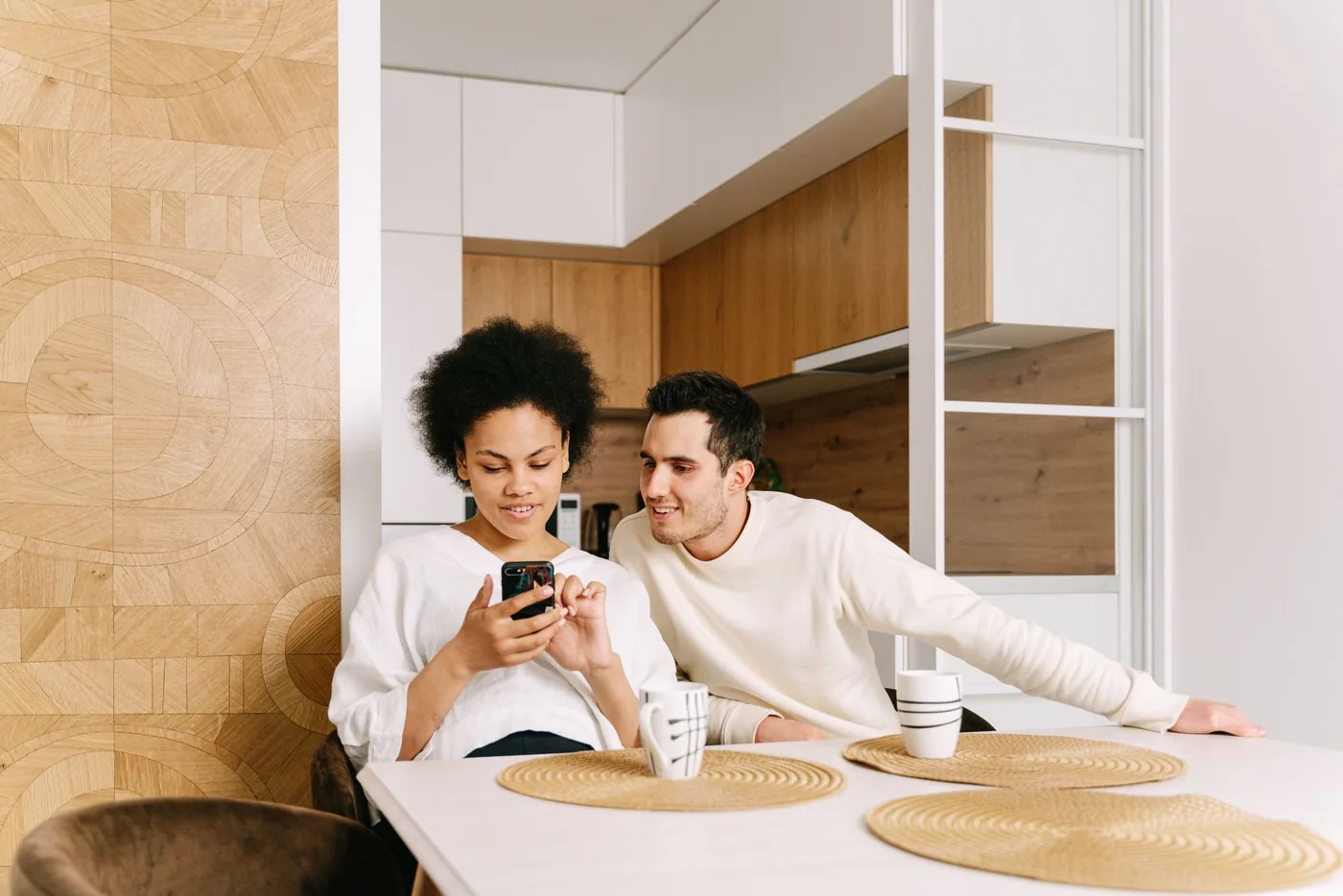 Couple sitting at their kitchen table looking at a phone together