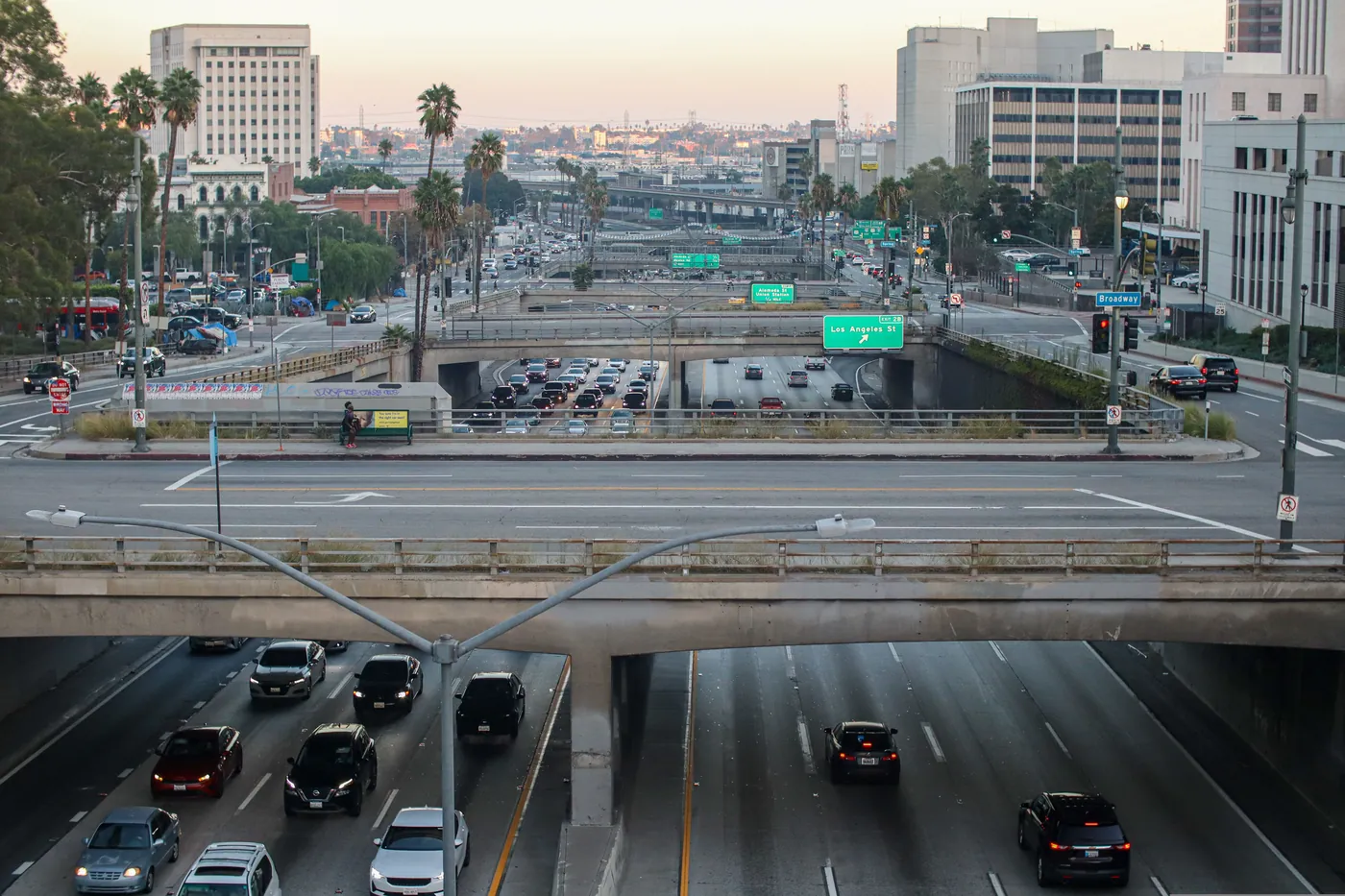 Cars filling a Los Angeles freeway beneath a row of overpasses in soft early light, the kind of traffic a third-shift drive home runs into.
