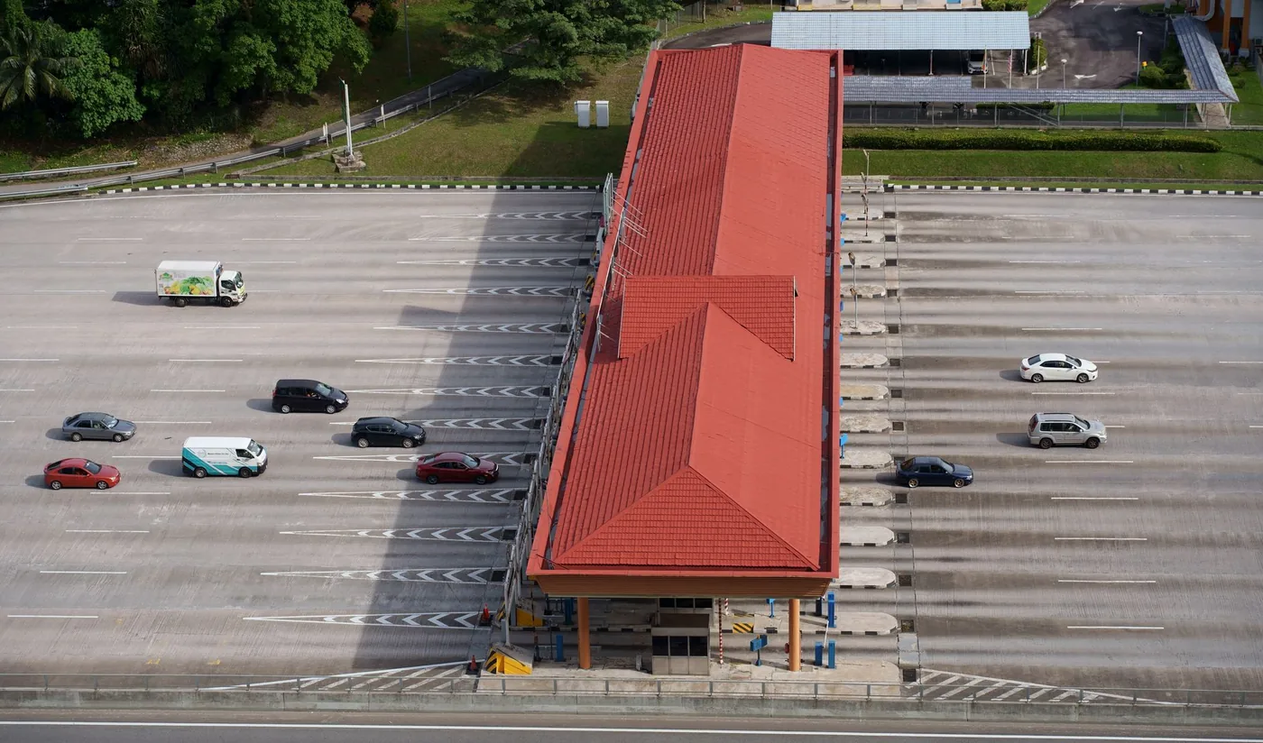 Aerial view of a multi-lane highway toll plaza with cars and trucks.