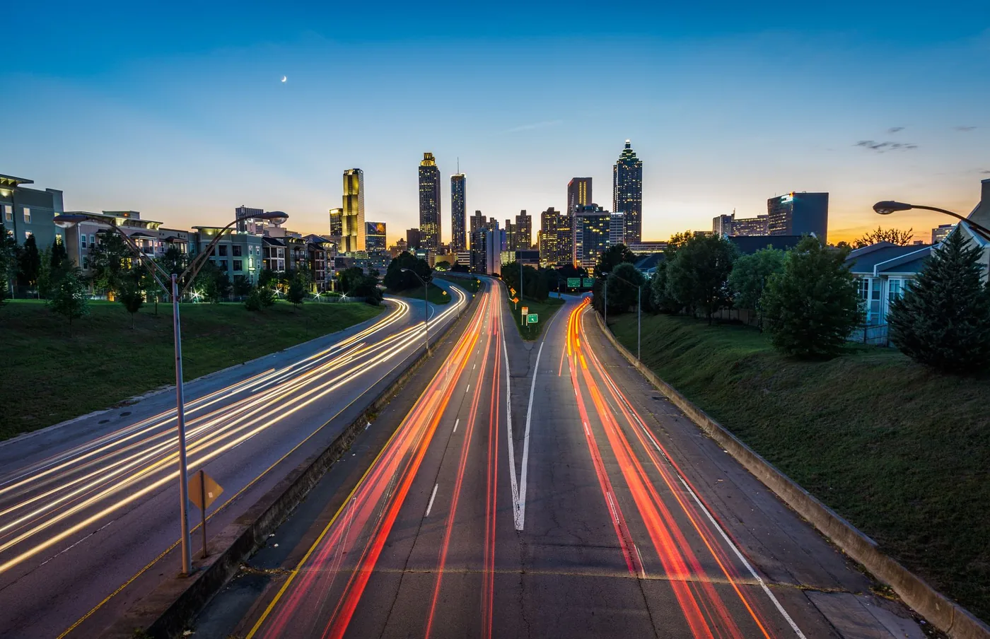 Stunning dusk view of Atlanta skyline with light trails on a busy highway, capturing urban vibrancy.