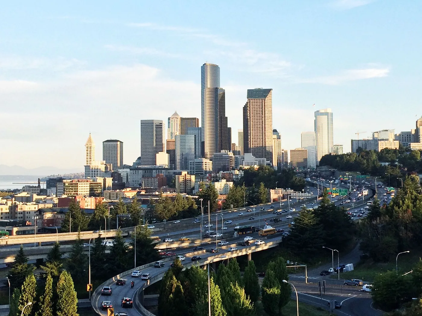 Panoramic view of Seattle's skyline and highway with bustling traffic under a clear sky.