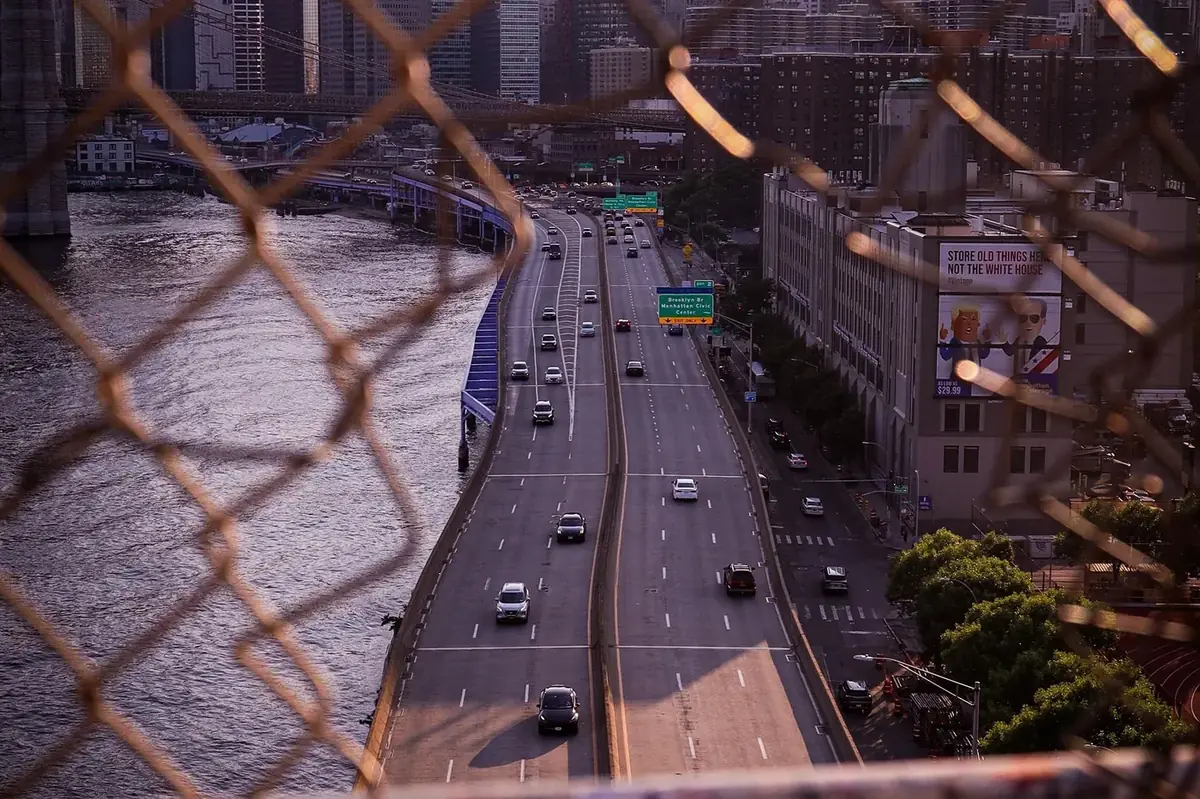 High-angle view of a New York City highway with traffic and the Manhattan skyline in the background.