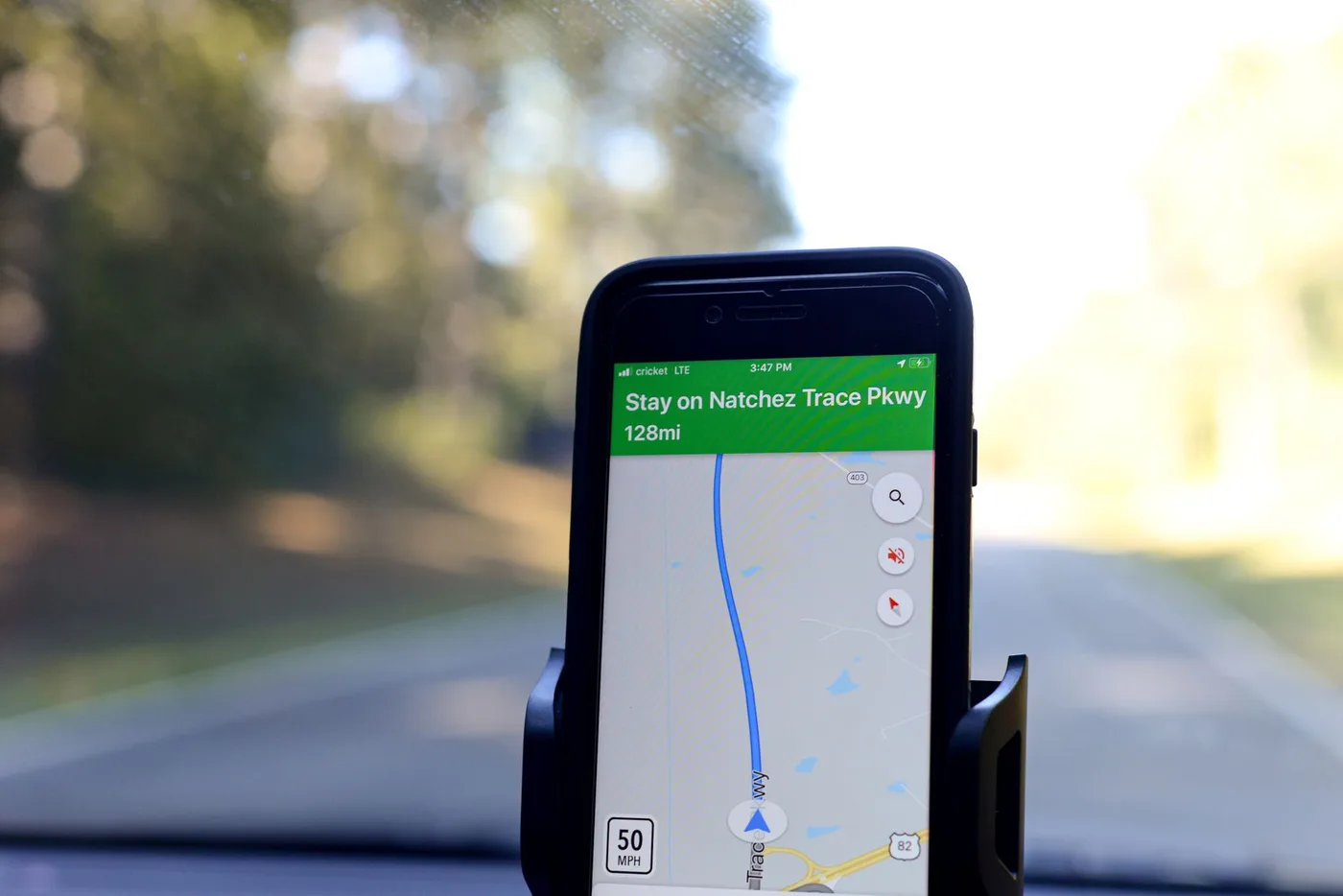 Smartphone displaying GPS navigation route on Natchez Trace Parkway inside a car.