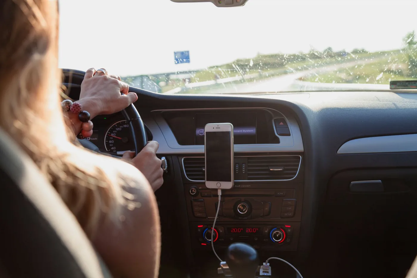 Driver's view of a hand on a car steering wheel during a commute.