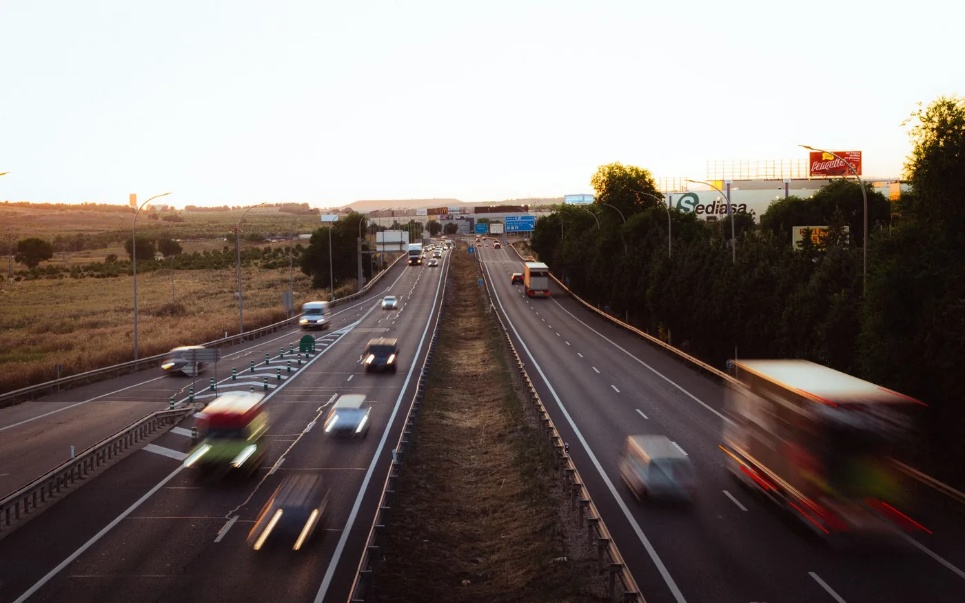 Aerial view of a busy multi-lane highway in Madrid, Spain during dusk, showcasing a dynamic travel scene.
