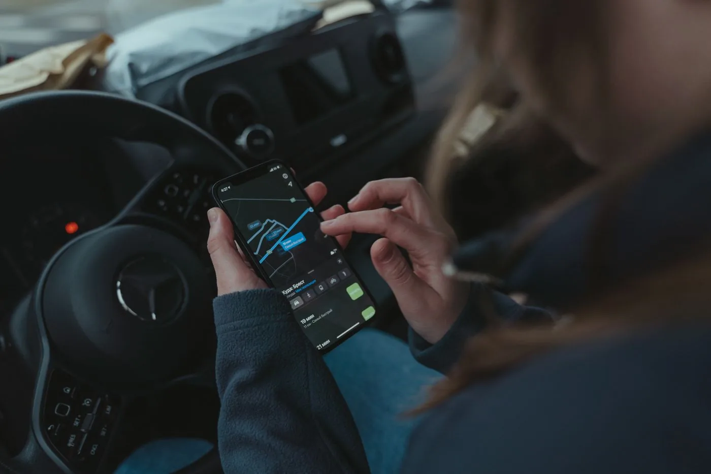 Person using a smartphone GPS navigation app inside a car.