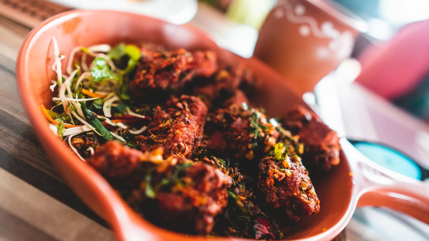 Close-up of a delicious spicy Indian chicken dish served with fresh garnish, vibrant colors.